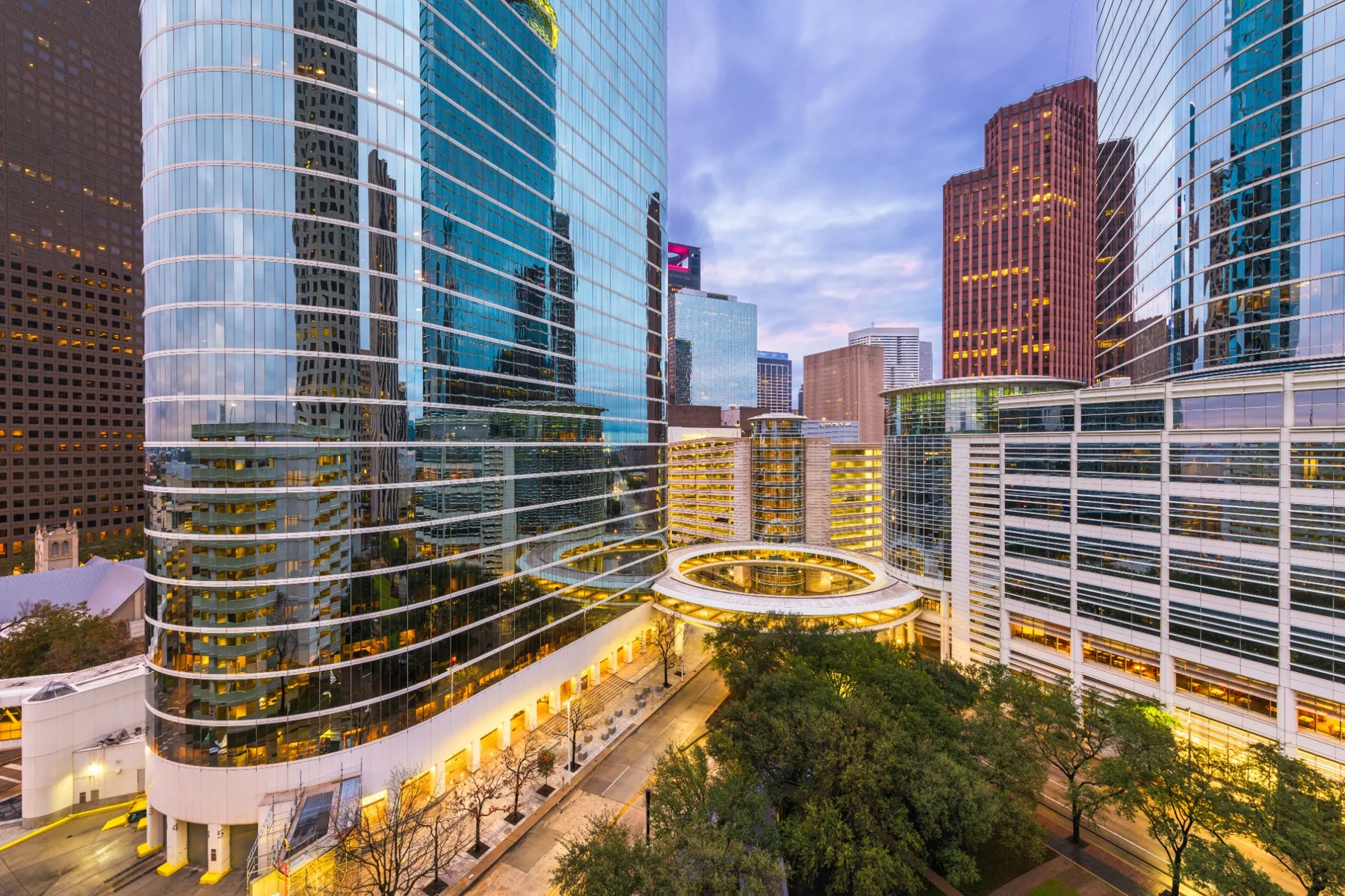 Illuminated glass-fronted Houston commercial office towers at dusk